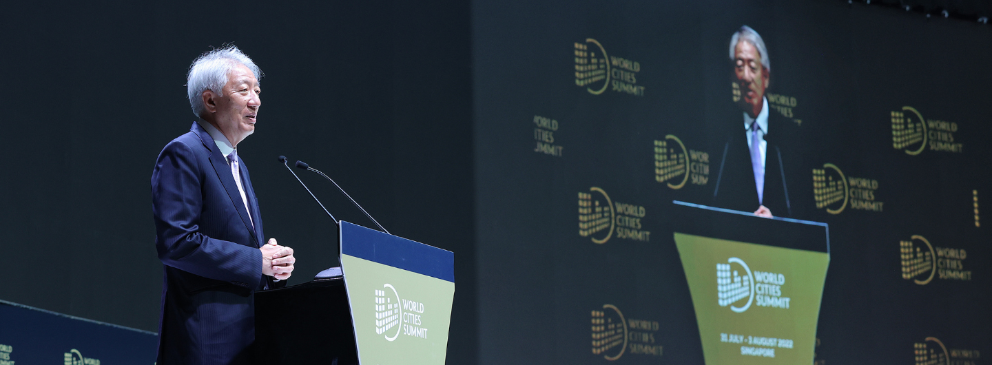 Speaker at World Cities Summit lectern, same man projected on large screen behind.